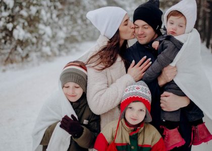 A joyful family enjoying a snowy day in a forest, wrapped in warm clothing.
