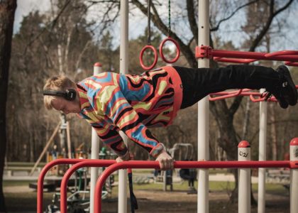 Young adult man exercises on outdoor gym bars in a colorful outfit in Vilnius, Lithuania.